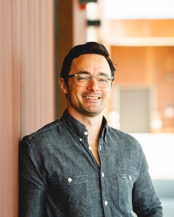 Michael Browne, smiling, in a chambray shirt and glasses.