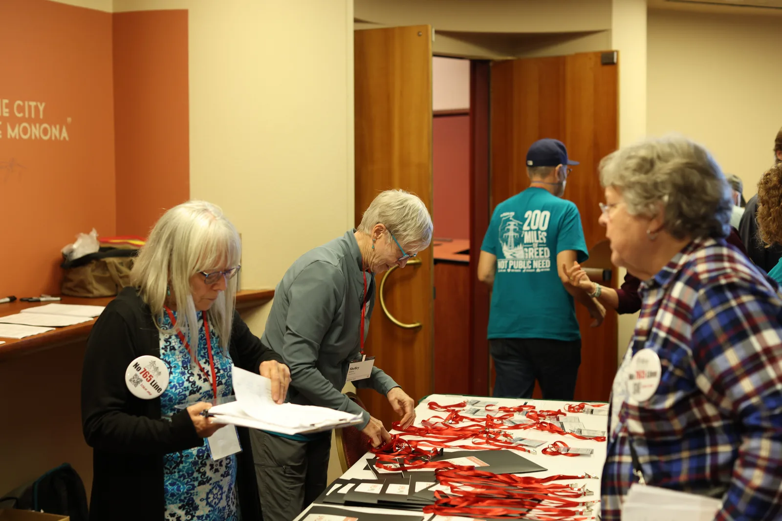 Photo 9 of 34. Volunteers at the check-in table hand out name badges and lanyards.