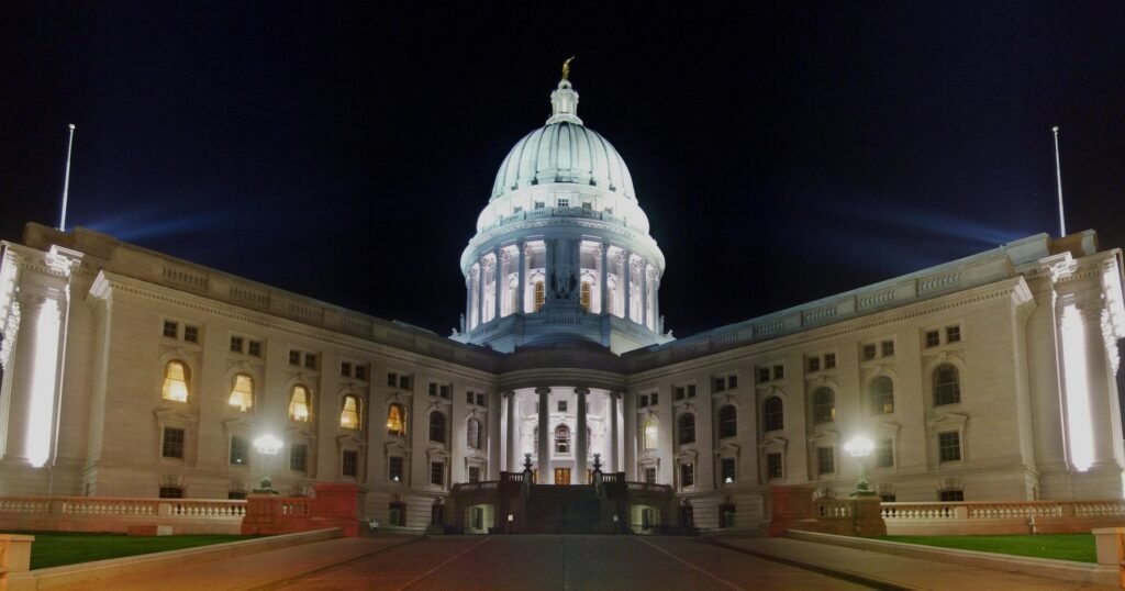 The Wisconsin State Capitol in Madison at night, lit from below, with the dome and both wings.