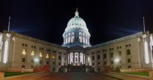The Wisconsin State Capitol in Madison at night, lit from below, with the dome and both wings.